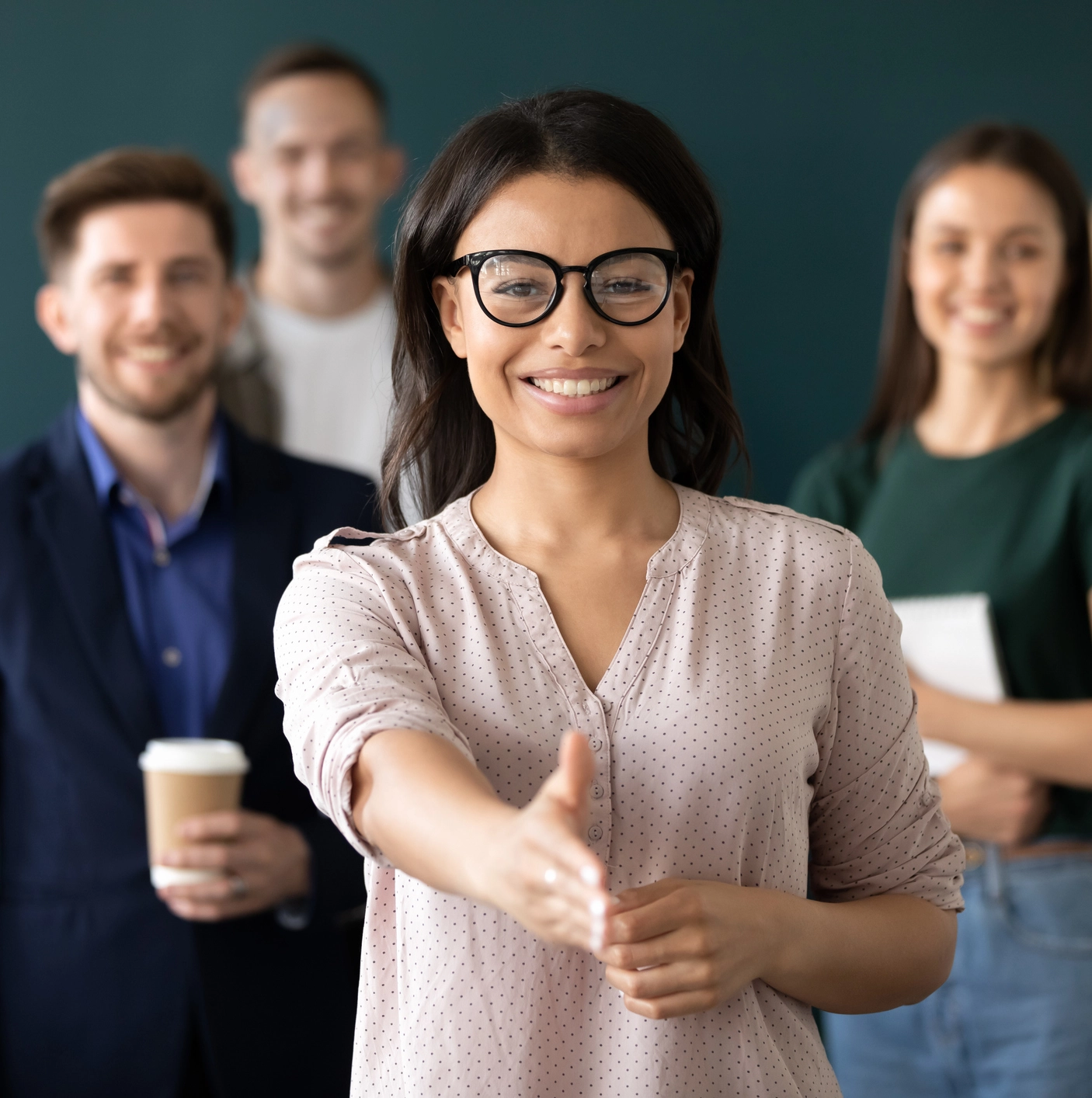 Woman extending hand for handshake, smiling.